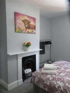 a room with a fireplace with a cow painting on the wall at 2 Railway Terrace 