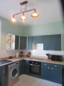 uma cozinha com armários azuis e uma máquina de lavar roupa em 2 Railway Terrace 