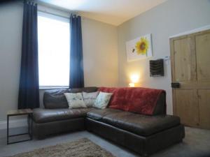 a living room with a leather couch and a window at 2 Railway Terrace in Croft