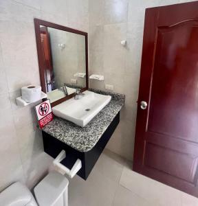 a bathroom with a sink and a mirror and a toilet at Hostal Villamil in Puerto Villamil