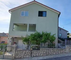 a white house with a stone fence in front of it at Klementina in Mali Lošinj