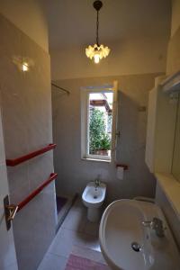 uma casa de banho com um lavatório, um WC e uma janela. em Bilocale a due passi dalla spiaggia em Marina di Campo