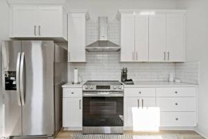 uma cozinha com armários brancos e um frigorífico de aço inoxidável em Urban Elegance Retreat em San Antonio