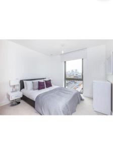 una camera bianca con un grande letto e una finestra di SweetHome Luxury Apartment a Londra