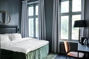 a bedroom with a bed and a desk and windows at Hotel Filip in Oslo