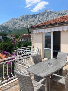 a wooden table and chairs on a balcony with a mountain at Apartmani Fani 2 min walking from sea in Orebić