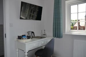 a white desk with a chair and a window at The Thorold in Marston