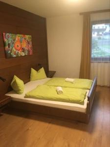 a bedroom with a bed with green sheets and a window at Aineterhof in Ainet