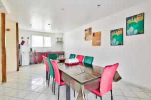 a dining room with a table and red chairs at Appartement meublé Dugny in Dugny