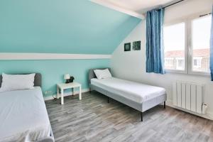 two beds in a room with blue walls and wooden floors at Appartement meublé Dugny in Dugny