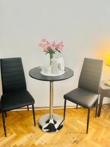 a table with two chairs and a vase with flowers on it at City Rooms in Budapest