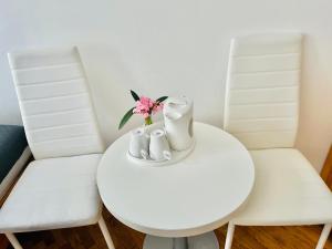 a white table with two chairs and a vase with flowers at City Rooms in Budapest
