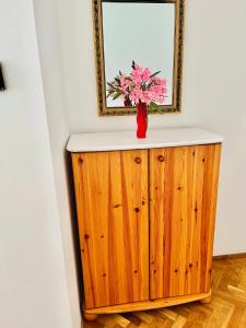 a vase with pink flowers on top of a wooden cabinet at City Rooms in Budapest