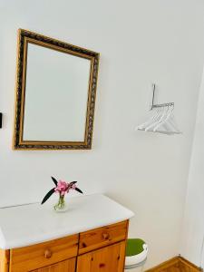 a bathroom with a mirror and a vase of flowers on a dresser at City Rooms in Budapest