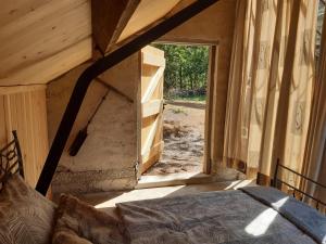 1 dormitorio con cama y ventana grande en Natuurslaapkamer de zaadeest boskamer, en Lomm