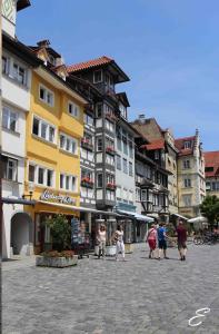 Un groupe de personnes marchant dans une rue avec des bâtiments dans l'établissement Bio-Ferienwohnung Ellensohn, à Lindau