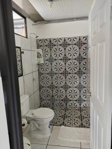 a bathroom with a toilet and a black and white tile wall at Hospedaje Eli 09 in Pavones