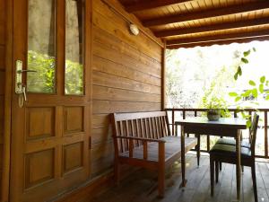 a porch with a wooden door and a table and bench at Endemik Bungalov in Edremit