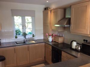 een keuken met houten kasten, een wastafel en een raam bij Liming Lodge - Lakeside Home in the Cotswolds in South Cerney