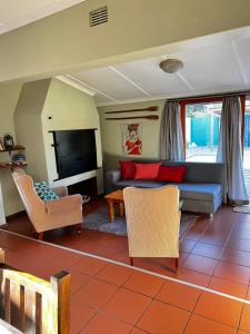 uma sala de estar com um sofá e uma televisão em Tuinhuis em Oudtshoorn