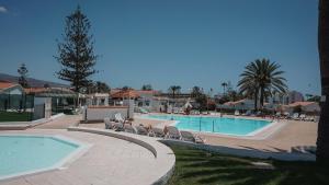 a swimming pool with lounge chairs next to a resort at BUNGALOW LOS ARCOS in Maspalomas
