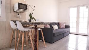 sala de estar con sofá y mesa con taburetes en BUNGALOW LOS ARCOS, en Maspalomas
