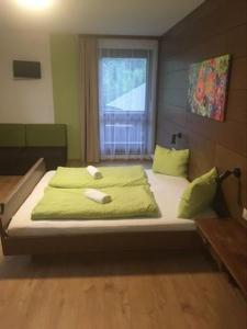 Schlafzimmer mit einem Bett mit grüner Bettwäsche und einem Fenster in der Unterkunft Aineterhof in Ainet