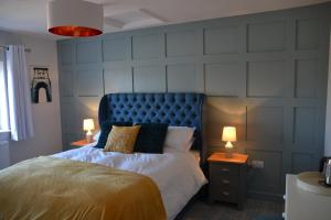 a bedroom with a bed with a blue headboard and two lamps at The Thorold in Marston