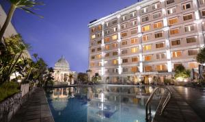 a hotel with a pool in front of a building at The Rich Jogja Hotel in Yogyakarta