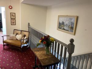 a staircase with a vase of flowers on a table and a chair at Thorverton Arms in Exeter