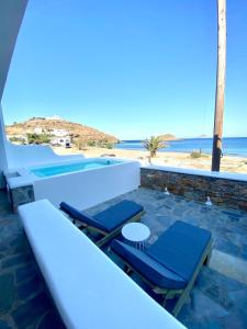 two chairs and a pool with the beach in the background at Villa Acta in Kithnos