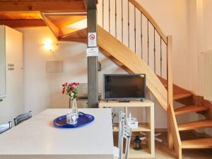 a room with a table with a tv and a staircase at Holiday Home Gelsomino-5 by Interhome in Consiglio di Rumo