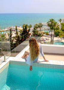 uma mulher sentada à beira de uma piscina em Royal Azur Thalassa em Hammamet