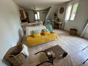 ein Wohnzimmer mit einem gelben Sofa und einem Tisch in der Unterkunft Le mas du bosc in Mauguio