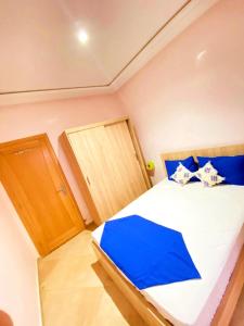 een slaapkamer met een groot bed met blauwe kussens bij Comfort apartment, with nice terrace (2min to sea) in Aourir