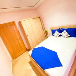 een slaapkamer met een bed met blauwe en witte kussens bij Comfort apartment, with nice terrace (2min to sea) in Aourir