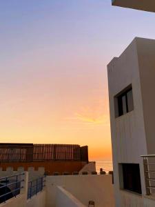 a view of a building with the sunset in the background at Comfort apartment, with nice terrace (2min to sea) in Aourir