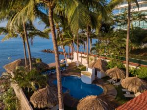 a resort swimming pool with palm trees and the ocean at Casa Mar&iacute;a Resort in Bucer&iacute;as
