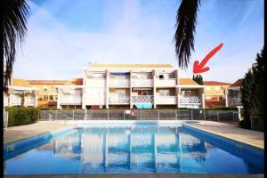 a building with a swimming pool in front of a building at Valras Plage - Appartement - 4 pers - piscine in Valras-Plage