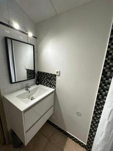 a white bathroom with a sink and a mirror at Le mas du bosc in Mauguio