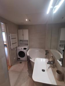 a bathroom with a tub and a sink and a washing machine at Vytauto 421 Apartments by JK in Palanga