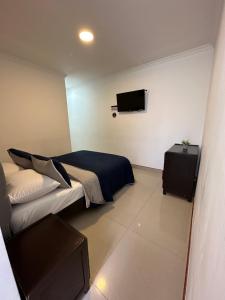 a bedroom with a bed and a flat screen tv at Hotel Paipa Inn in Paipa