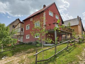 una casa rossa con una recinzione di fronte di Apartmani Sobe Sljivancanin a Žabljak