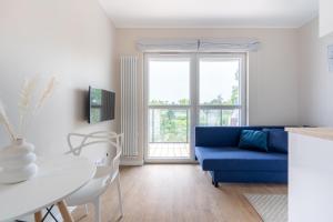 a living room with a blue couch and a table at Brzeźno Studio Deluxe in Gdańsk
