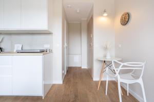 a kitchen with white cabinets and a table and a chair at Brzeźno Studio Deluxe in Gdańsk