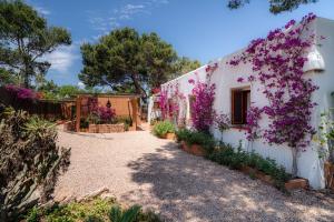 een huis met paarse bloemen erop bij Can Tamarix in La Savina