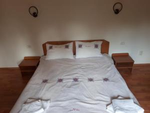 a large bed with white sheets and pillows on it at Casa Ionel si Dani in Fundata