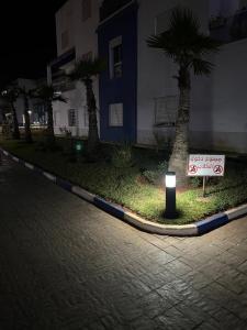 - un panneau de stationnement sans panneau à côté d'un bâtiment avec des palmiers dans l'établissement Les terrasses, à Mohammedia