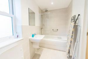 a white bathroom with a sink and a bath tub at Stylish Open Plan City Apartment in Bath
