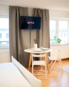 una mesa y sillas en una habitación con un cartel de netflix en Centre Apartment, en Leipzig